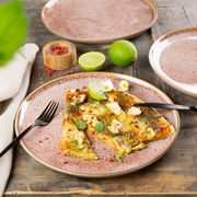 Geschirrset Terra 18-tlg. mit floralem Muster, präsentiert mit einer Pizza und Limetten auf einem Holztisch, aus der Vogelperspektive.