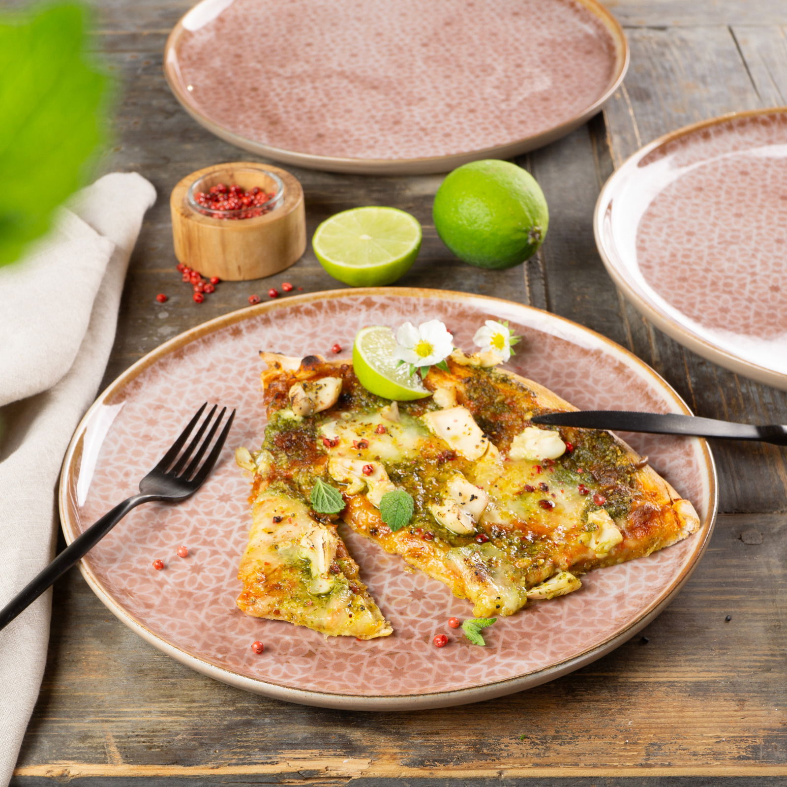 Moritz & Moritz Geschirrset 18-tlg. TERRA Geschirrset Terra 18-tlg. mit floralem Muster, präsentiert mit einer Pizza und Limetten auf einem Holztisch, aus der Vogelperspektive.