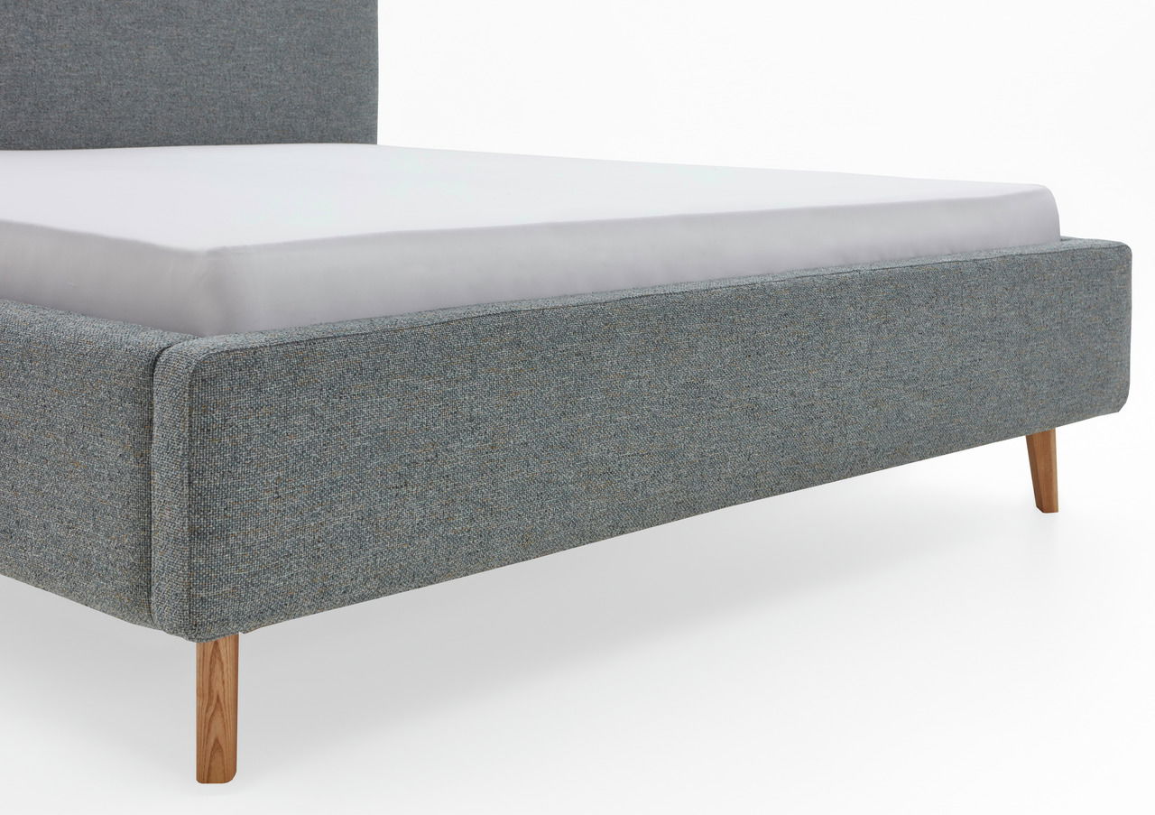 Seitliche Perspektive eines grauen Polsterbettgestells mit Holzbeinen.