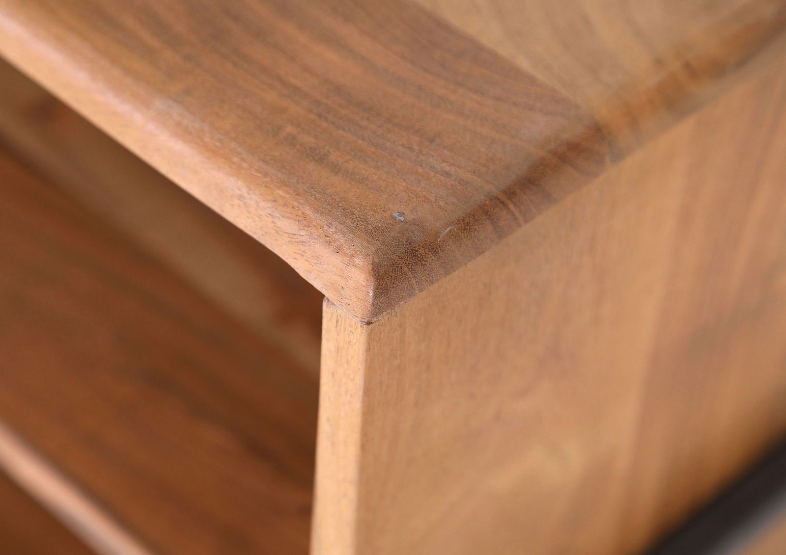 Nahaufnahme einer Ecke eines Lowboards aus Holz mit glatter Oberfläche und abgerundeten Kanten.