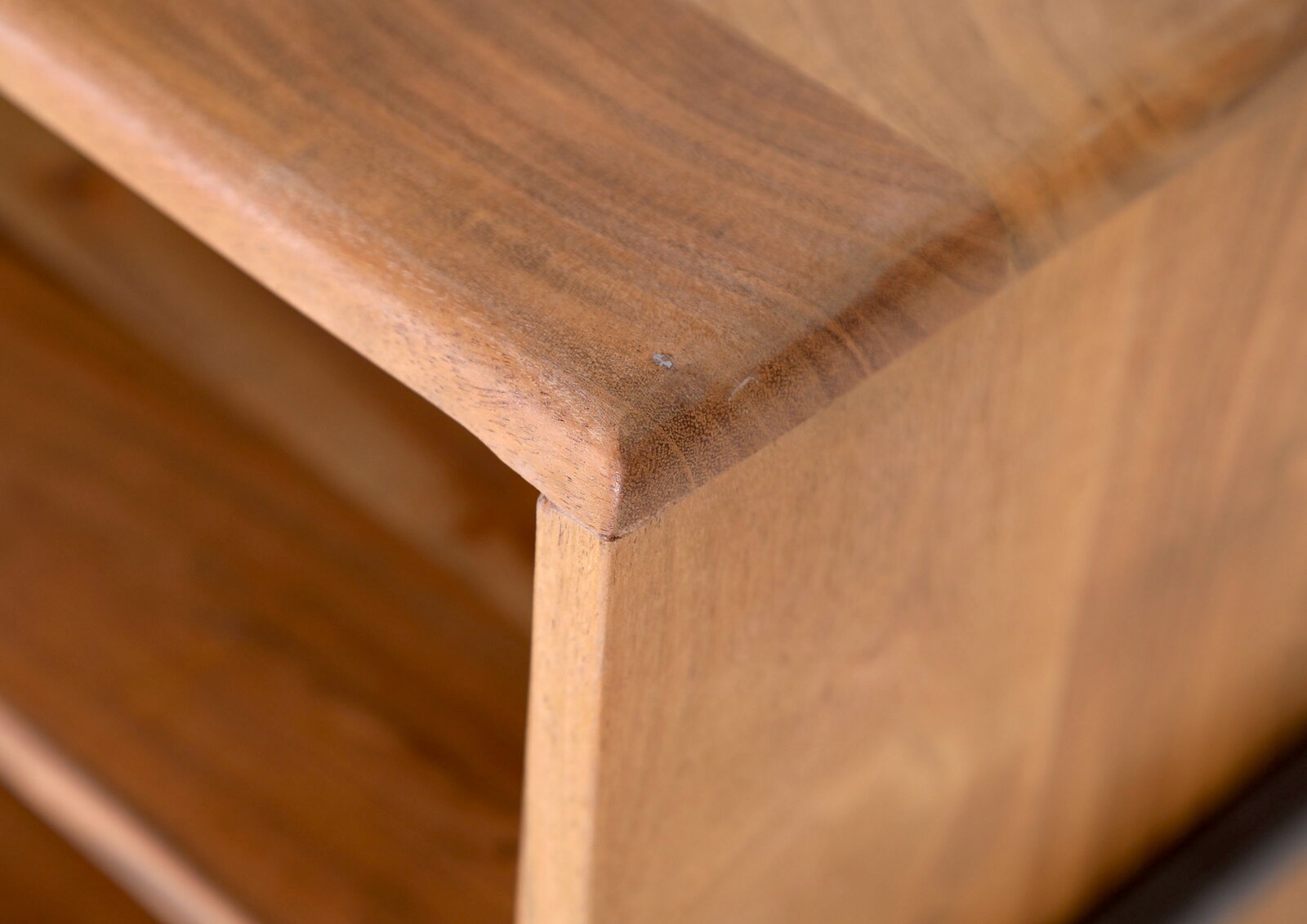 LOMOCO Lowboard PURO Close-up van een hoek van een houten lowboard met een glad oppervlak en afgeronde randen.