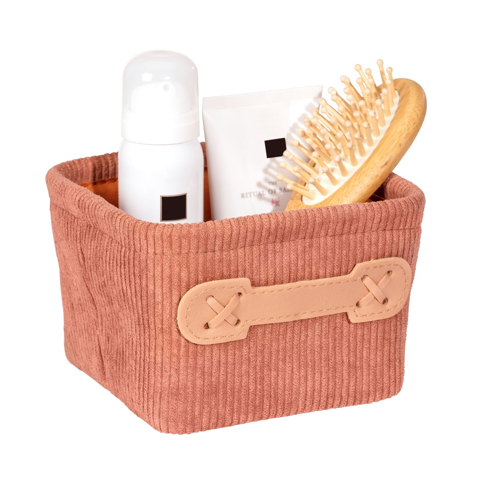 Kleiner quadratischer Badkorb in Altrosa mit Kordstruktur, gefüllt mit einer Haarbürste, einer Flasche und einer Tube, seitliche Perspektive.