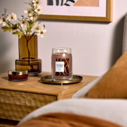 Brennende Yankee Candle Cinnamon Stick Duftkerze im großen Glas mit zwei Dochten, frontal aus leicht erhöhter Perspektive auf einem goldfarbenen Tablett in gemütlichem Wohnambiente inszeniert