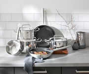 Küchenansicht mit einem sechsteiligen Topfset aus Edelstahl, bestehend aus Töpfen und Pfannen, auf einer Arbeitsplatte. Die Perspektive zeigt die glänzende Oberfläche und die robuste Bauweise der Töpfe.