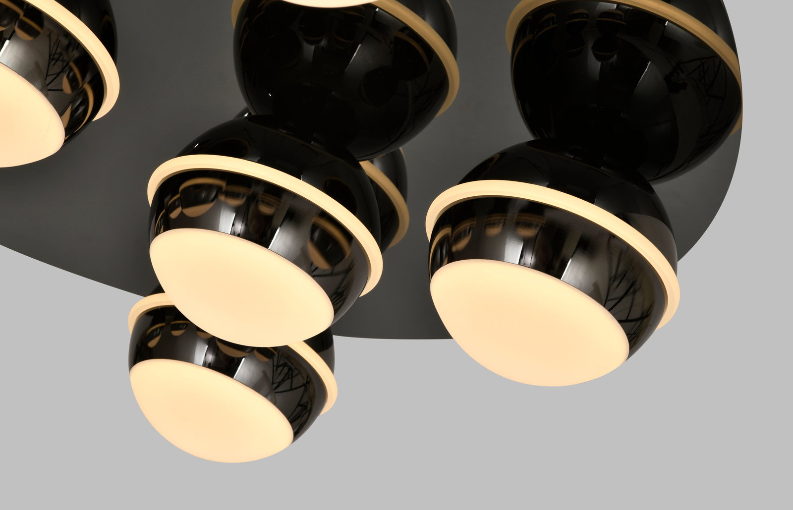 Moderne LED-Deckenleuchte mit mehreren kugelförmigen, schwarz glänzenden Lampenschirmen und warmweißen Lichtquellen, seitliche Perspektive.