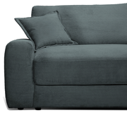 Großes Sofa in dunkelgrauem Cordstoff, seitliche Perspektive mit Kissen auf der linken Armlehne.