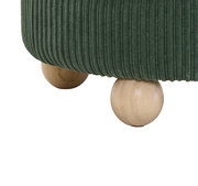 Nahaufnahme eines grünen Hockers mit geripptem Stoffbezug und runden Holzfüßen, seitliche Perspektive