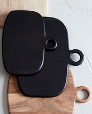 Drei übereinander gestapelte Schneidebretter aus Holz, zwei in dunklem Holzton und eines in hellem Holzton, mit runden Griffen, aus der Vogelperspektive fotografiert.