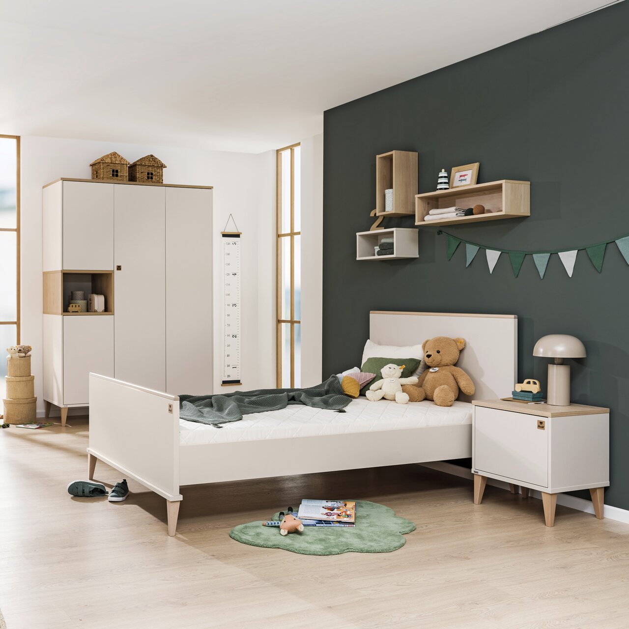 Paidi Nachtkastje MILA&BEN Kinderkamer met een modern nachtkastje, gezien vanaf de zijkant, naast een bed met knuffels en een lamp.
