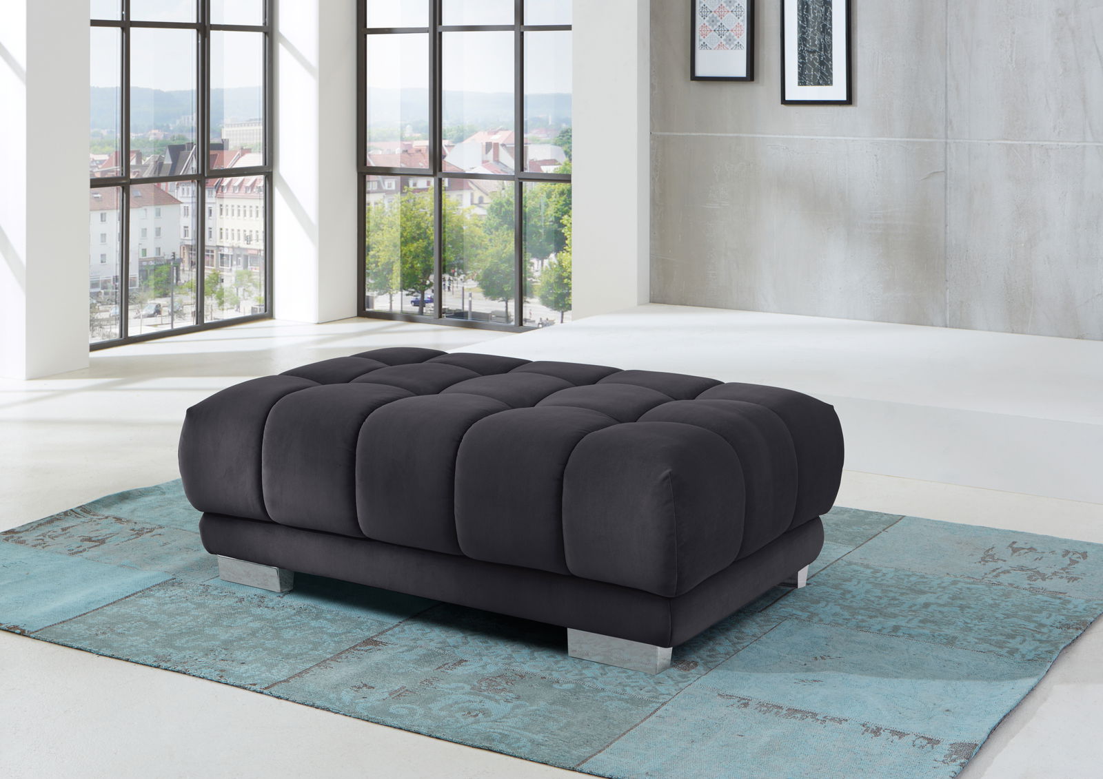 XXL-Hocker in modernem Wohnzimmer, seitliche Perspektive, mit großen Fenstern im Hintergrund.