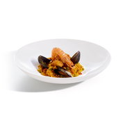 Meeresfrüchte-Paella mit Garnele und Miesmuscheln in einem tiefen weißen Teller, in leichter Seitenansicht (3/4-Perspektive) vor hellem Hintergrund.