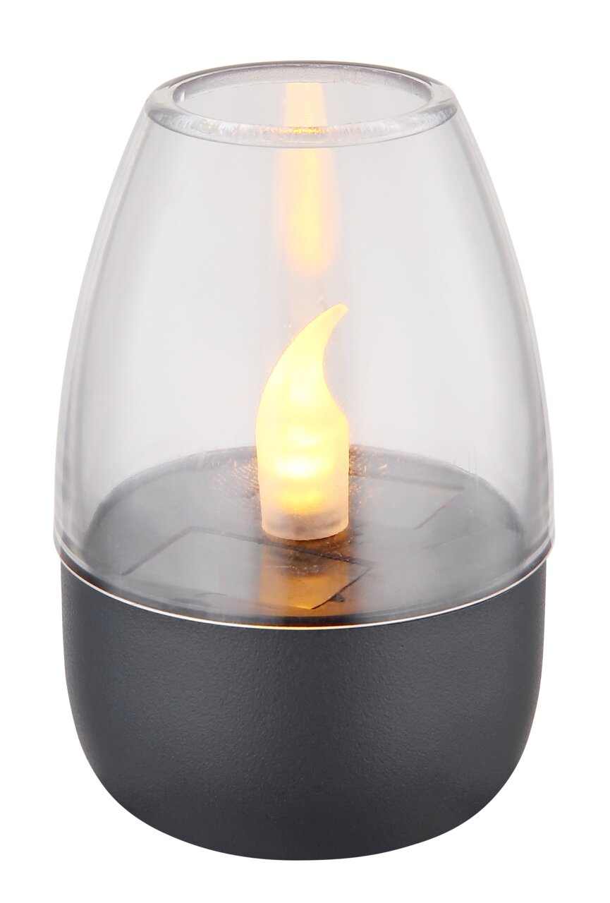 Nahaufnahme einer Solarleuchte mit flammenförmigem LED-Licht in einem transparenten Gehäuse auf einem dunklen Sockel.