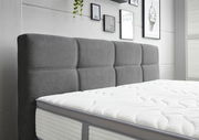 Graues Boxspringbett mit gepolstertem Kopfteil, seitliche Perspektive