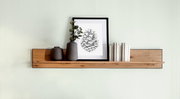 Wandboard aus Holz mit Dekoration, darunter zwei Vasen, ein gerahmtes Bild und Bücher, aus frontaler Perspektive.