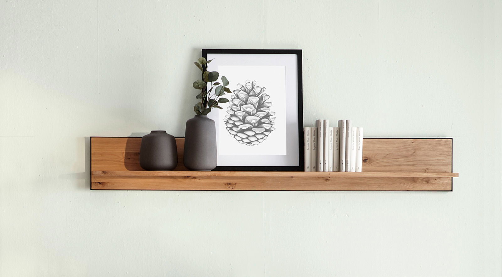 Wandboard aus Holz mit Dekoration, darunter zwei Vasen, ein gerahmtes Bild und Bücher, aus frontaler Perspektive.