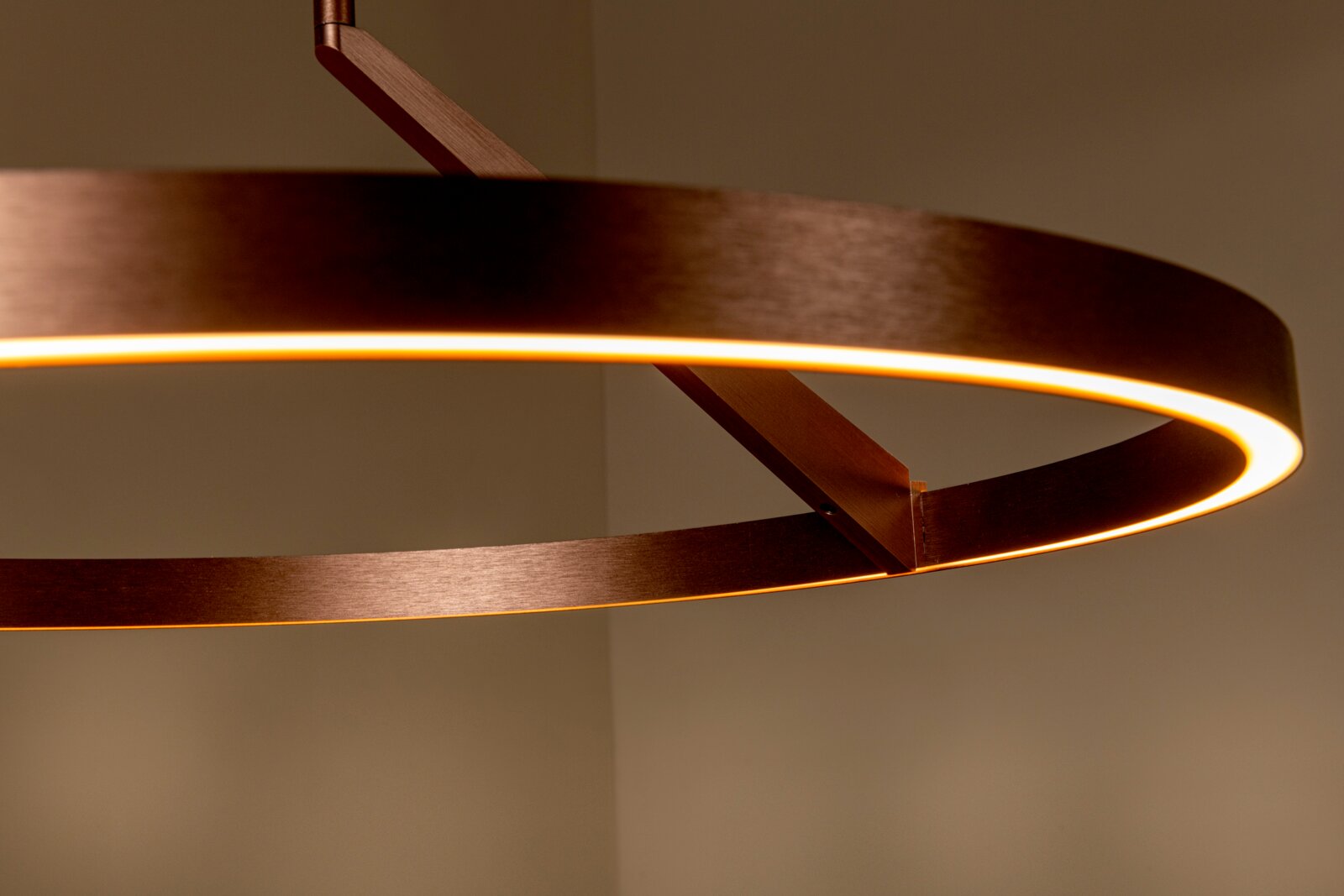 Moderne runde LED-Pendelleuchte in Kupferoptik mit warmweißem Licht, Detailaufnahme aus leicht seitlicher Untersicht