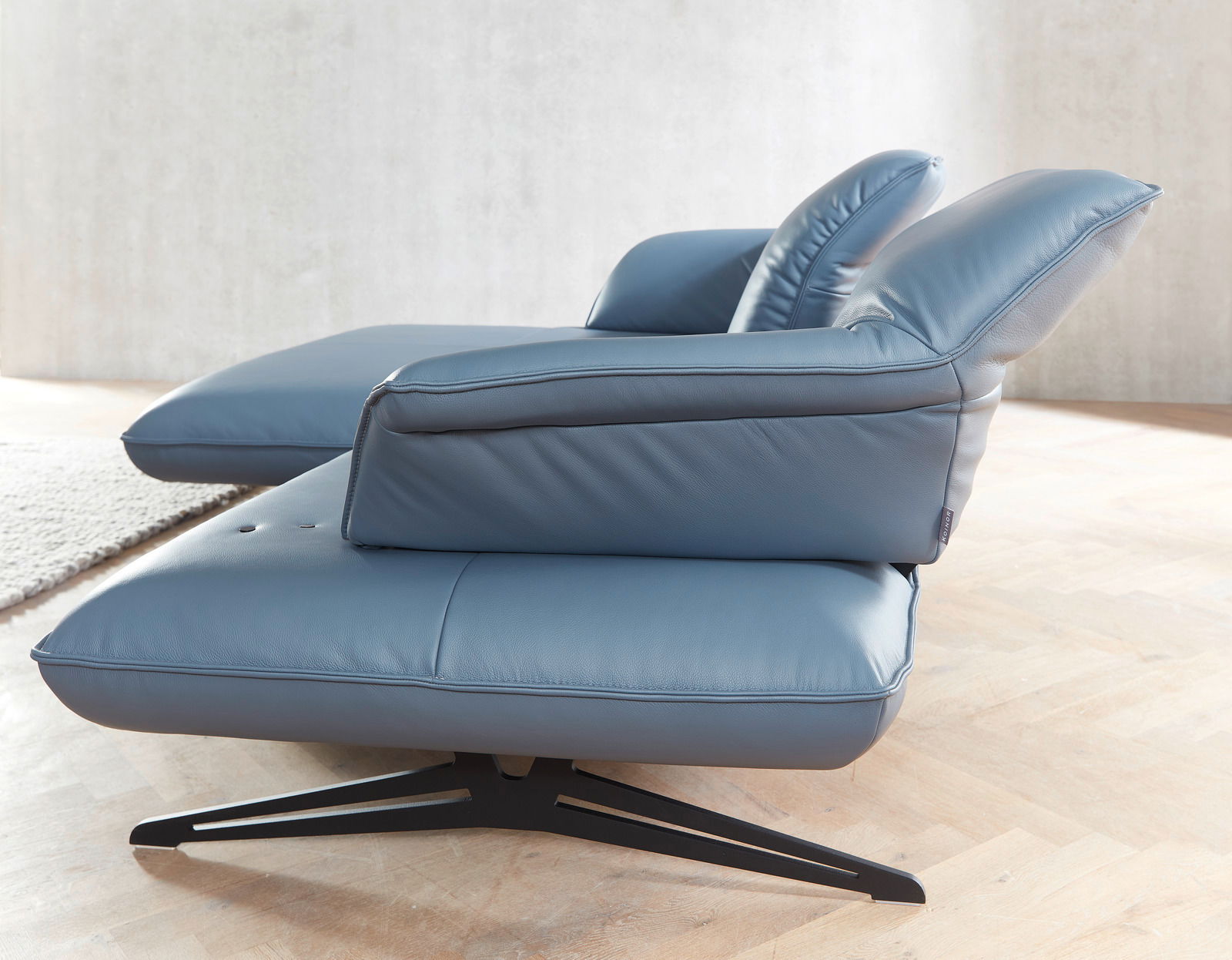 Seitenansicht einer blauen Koinor Longchairkombination SEVENTY mit modernem Design und Metallfuß auf Holzfußboden.