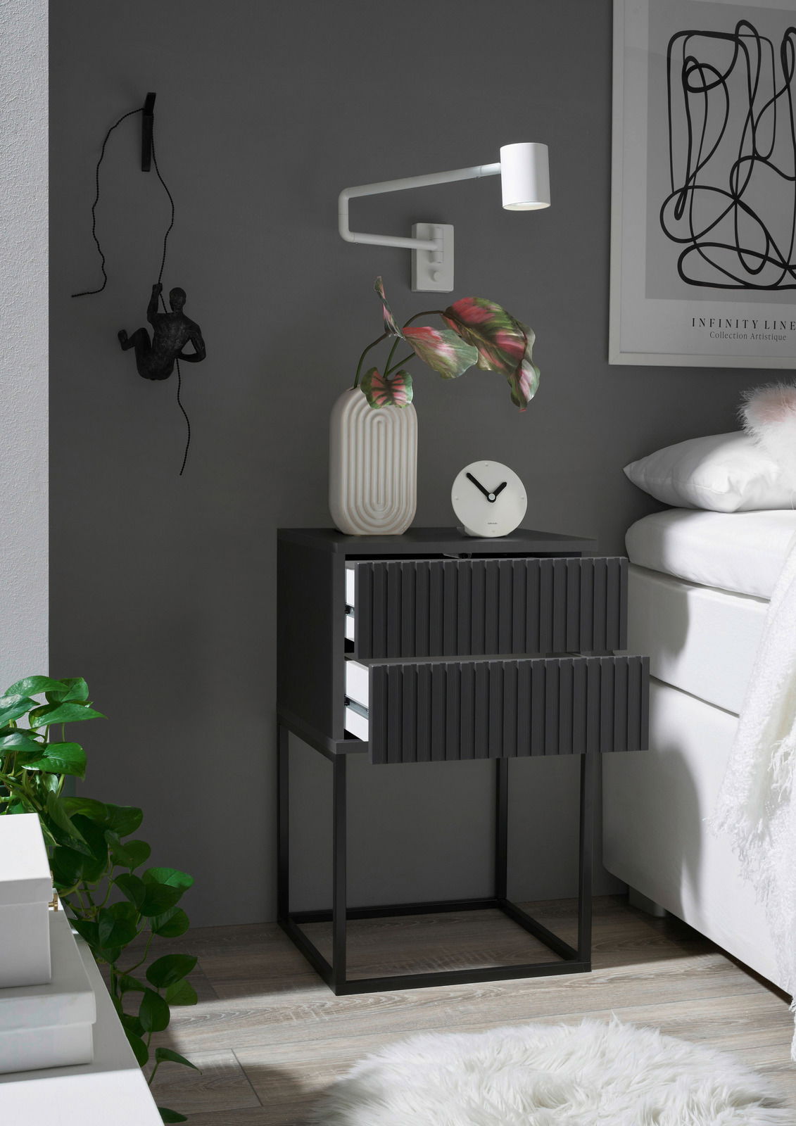 Moderne Nachtkommode mit zwei Schubladen in dunklem Design, seitliche Perspektive, dekoriert mit einer Vase und einer Uhr.