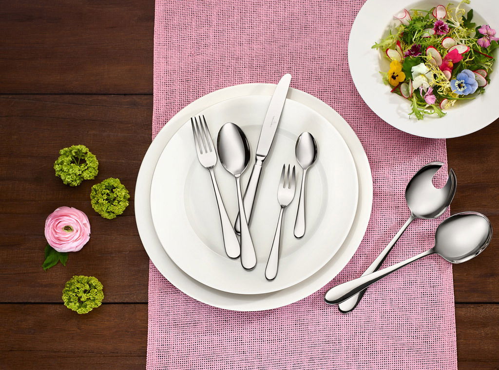 Villeroy & Boch Tafelbesteck 68-tlg.OSCAR Elegantes Tafelbesteck-Set Oscar, 68-teilig, auf einem gedeckten Tisch mit rosa Tischläufer und dekorativen Blumen, aus der Vogelperspektive fotografiert.
