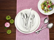 Elegantes Tafelbesteck-Set Oscar, 68-teilig, auf einem gedeckten Tisch mit rosa Tischläufer und dekorativen Blumen, aus der Vogelperspektive fotografiert.