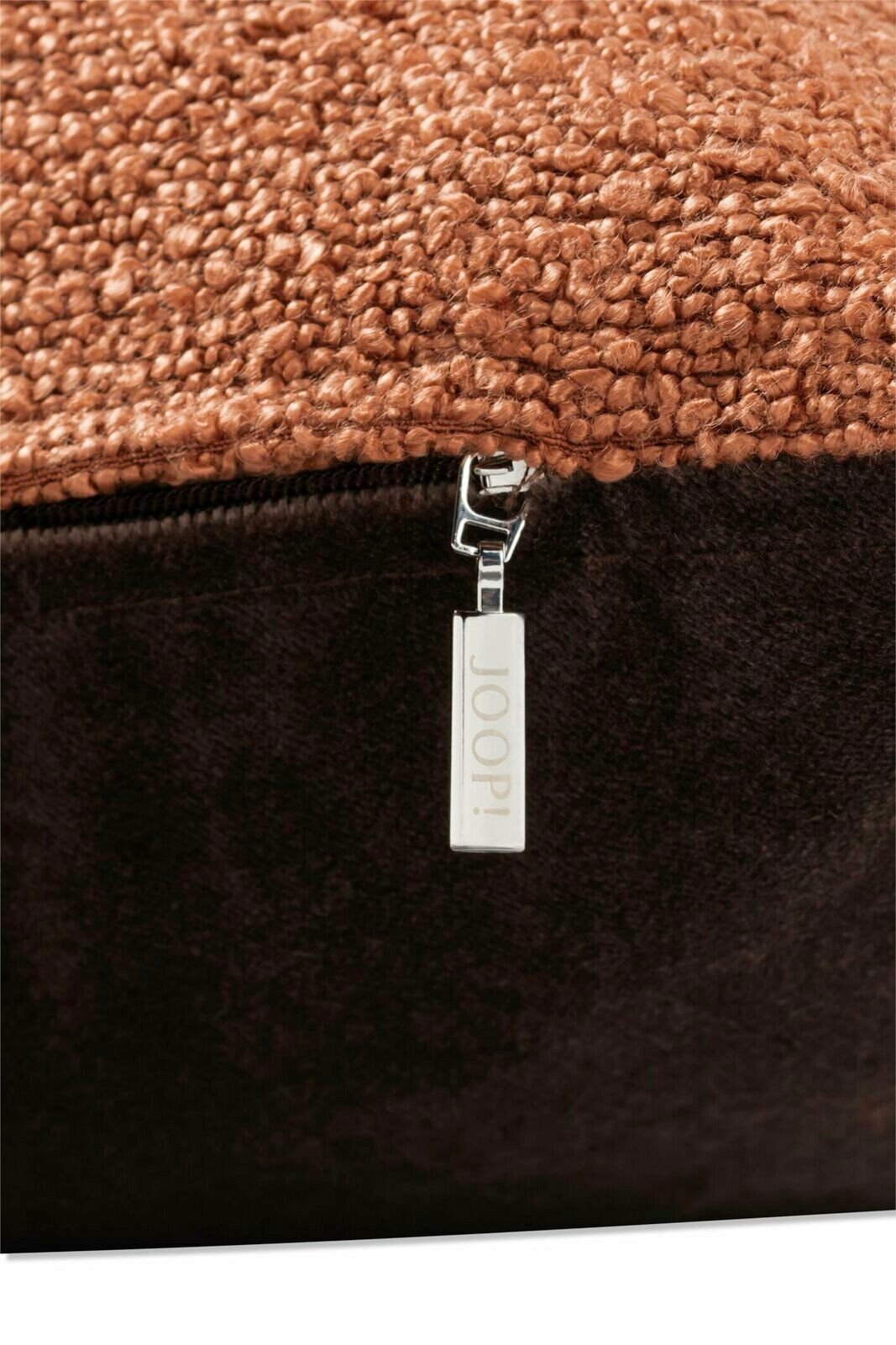 Nahaufnahme einer Zierkissenhülle mit grober Textur und einem Reißverschluss mit der Aufschrift 'JOOP!'