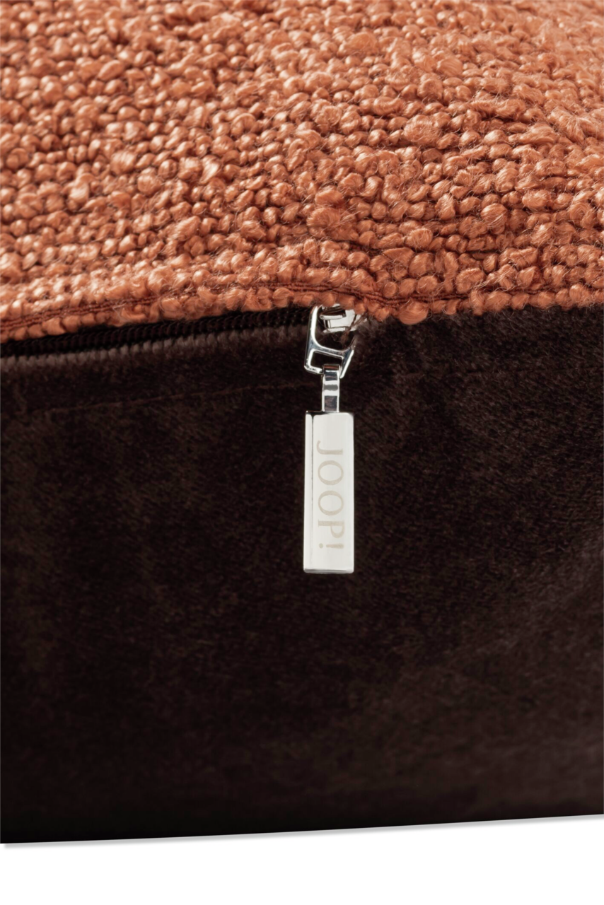 Nahaufnahme einer Zierkissenhülle mit grober Textur und einem Reißverschluss mit der Aufschrift 'JOOP!'