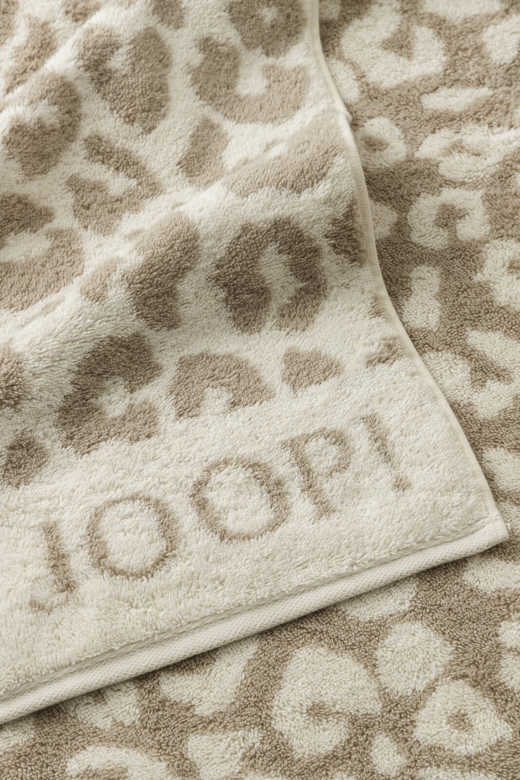 Beige handdoek met luipaardprint en JOOP!-logo, gefotografeerd vanuit vogelperspectief.