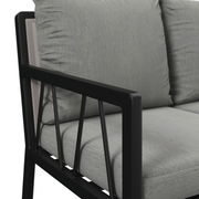 Nahaufnahme einer Gartenbank mit grauen Kissen und schwarzem Metallrahmen, seitliche Perspektive