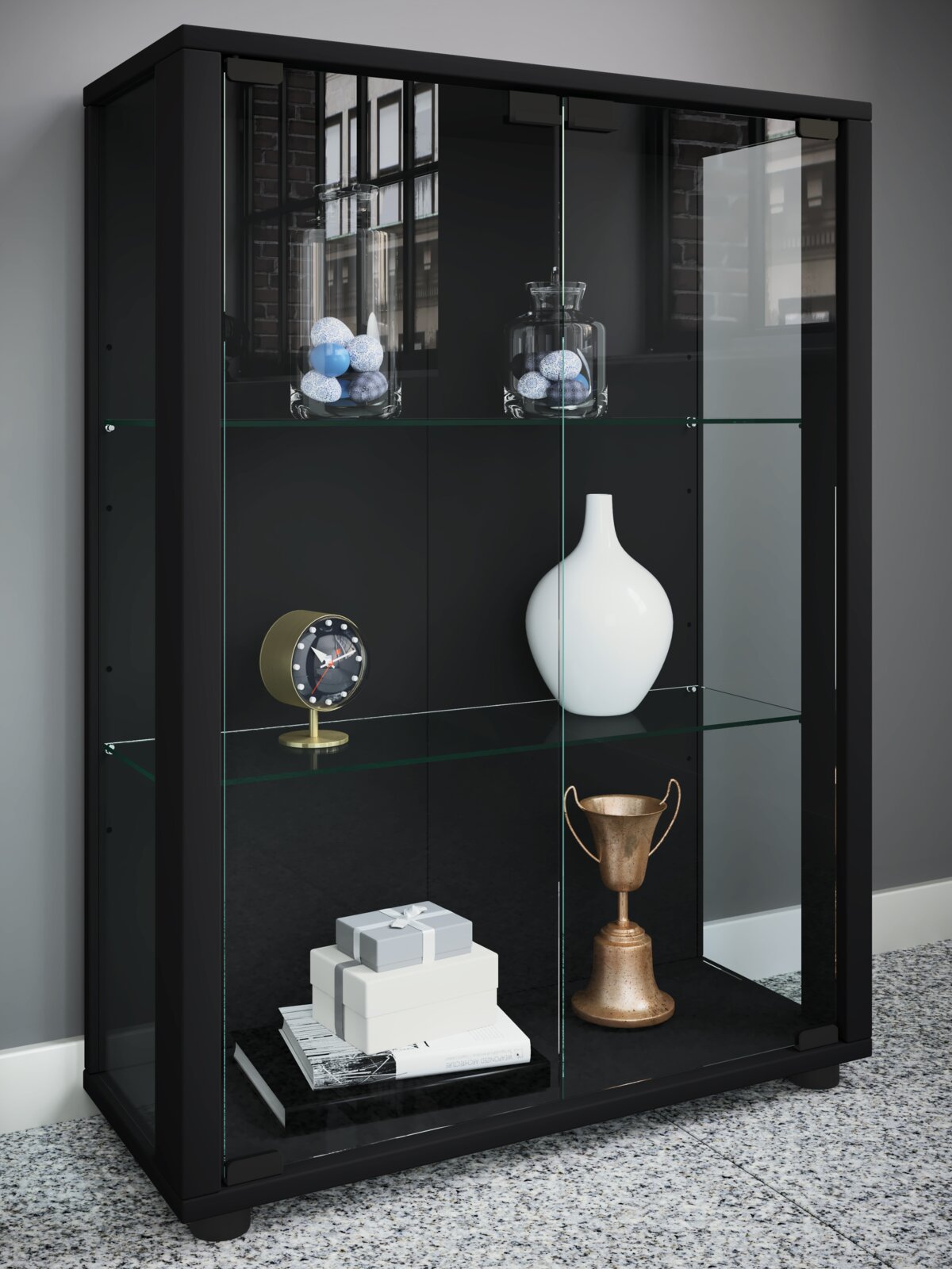 Schwarze Vitrine mit Glasböden und Schiebetüren, dekoriert mit Vasen, Uhr, Geschenkboxen und Pokal; Perspektive: frontale Ansicht leicht von links.