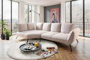 Beige Longchairkombination in einem modernen Wohnzimmer mit großen Fenstern, Pflanzen und einem runden Teppich, seitliche Perspektive.