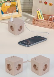 Steckdosenwürfel mit mehreren Steckplätzen und USB-Anschlüssen, beige Farbe, auf einem Schreibtisch platziert, mit einem angeschlossenen Smartphone. Perspektive von oben und seitlich.