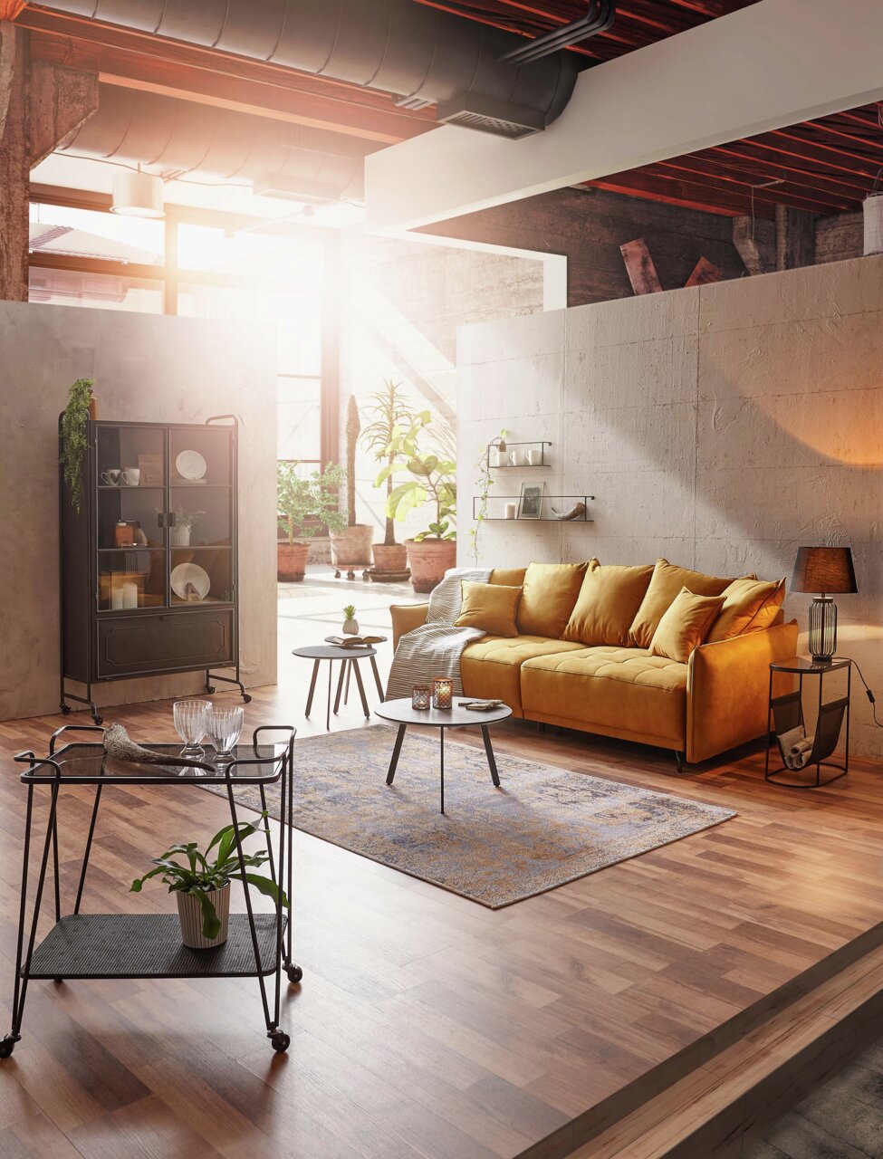 Gemütliches Wohnzimmer mit einem großen, senfgelben Sofa in einem modernen Loft-Ambiente, seitliche Perspektive.