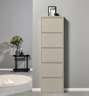 Hoher, schmaler Schuhschrank in Beige mit fünf Klappfächern, frontal aus leicht seitlicher Perspektive vor grauer Wand; oben Deko mit Bild und Schale, daneben Beistelltisch mit Vase.