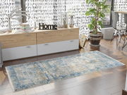 Designer Teppich in Blau- und Beigetönen auf einem Holzboden in einem modernen Wohnzimmer mit seitlicher Perspektive.