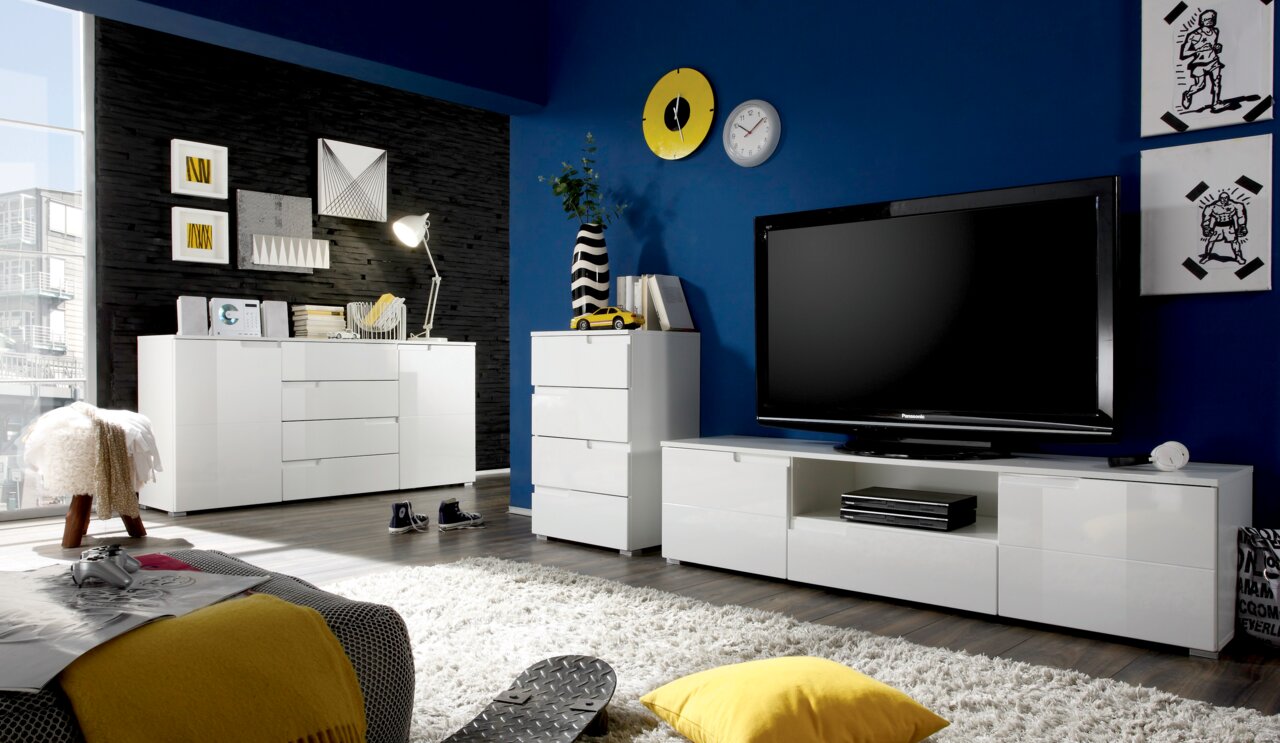 BOXXX Hochkommode SILAS Moderne Wohnzimmermöbel in Weiß, bestehend aus einer Kommode, einem TV-Lowboard und einem Highboard, in einem stilvoll eingerichteten Raum mit blauer Wand und Dekorationen. Perspektive: Frontalansicht.