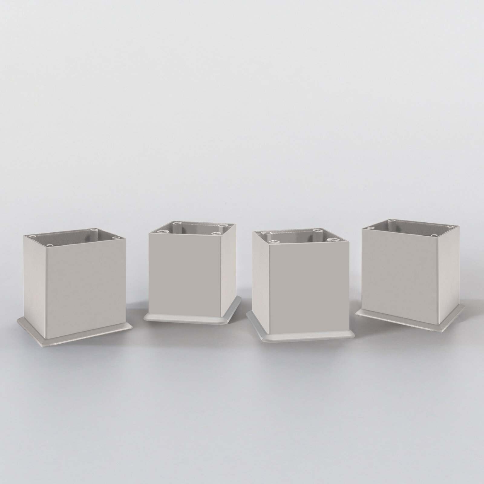Vier silberne, quadratische Möbelbeine aus Metall, frontal betrachtet, auf einer weißen Oberfläche stehend.