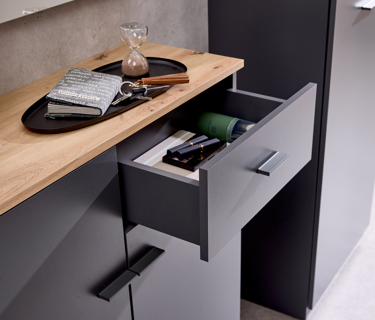 Kompaktgarderobe mit geöffneter Schublade, Holzoberfläche und modernen Griffen, aus der Vogelperspektive fotografiert.