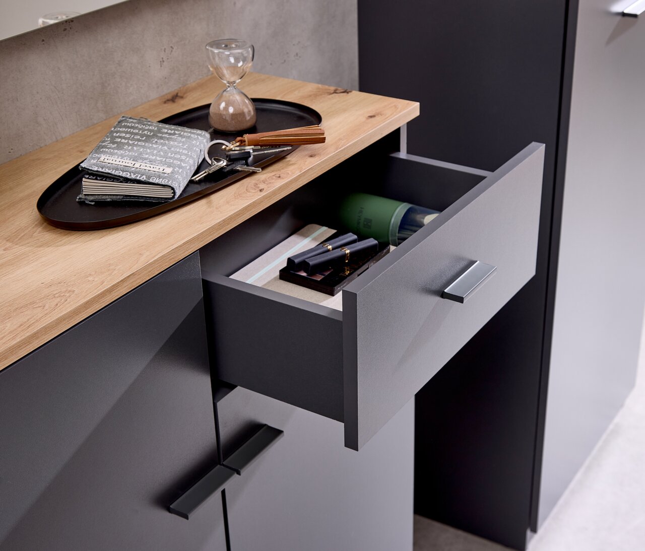 Kompaktgarderobe mit geöffneter Schublade, Holzoberfläche und modernen Griffen, aus der Vogelperspektive fotografiert.