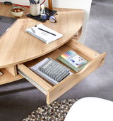Eckschreibtisch aus Holz mit geöffneter Schublade, gefüllt mit Notizbüchern und Stiften, aus der Vogelperspektive fotografiert.