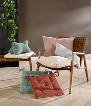 Sitzkissen in verschiedenen Farben auf einem Stuhl und Boden, seitliche Perspektive