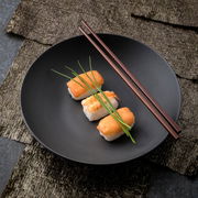 Schwarze Schale mit Sushi und Essstäbchen, von oben fotografiert