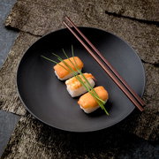 Schwarze Schale mit Sushi und Essstäbchen, von oben fotografiert