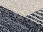 Nahaufnahme eines Frisé-Teppichs mit grauen und cremefarbenen Streifenmuster, diagonale Perspektive.