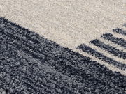 Nahaufnahme eines Frisé-Teppichs mit grauen und cremefarbenen Streifenmuster, diagonale Perspektive.