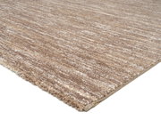 Beige-brauner Uni-Teppich in Nahaufnahme, perspektivisch von der Seite fotografiert.