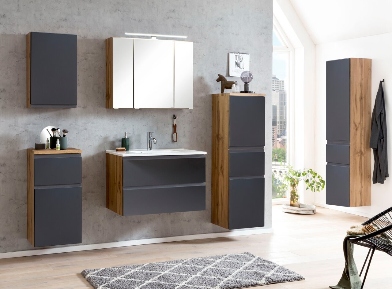 Moderne Badezimmermöbel in Holzoptik mit grauen Fronten, inklusive Hochschrank, aus seitlicher Perspektive fotografiert.