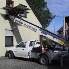 Ein Sofa, das mit Hilfe eines Flaschenzuges aus dem Fenster gehievt wird, bei klarem Himmel.