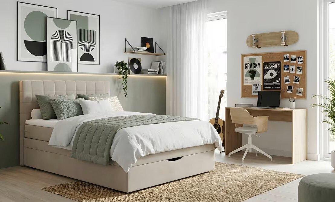 Modernes Schlafzimmer mit beigem Polsterbett mit gepolstertem Kopfteil und Bettkasten, weißer Bettwäsche und grüner Tagesdecke, daneben Schreibtisch und Pinnwand; Perspektive: frontale, leicht seitliche Weitwinkelansicht.
