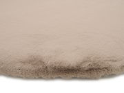 Nahaufnahme eines beigen Fellteppichs mit weicher Textur, von der Seite betrachtet.