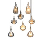 Set aus sieben modernen Pendelleuchten mit tropfen- und kugelförmigen Glas-Schirmen in Rauchgrau und Amber, warm leuchtend, frontal in leichter Untersicht vor weißem Hintergrund